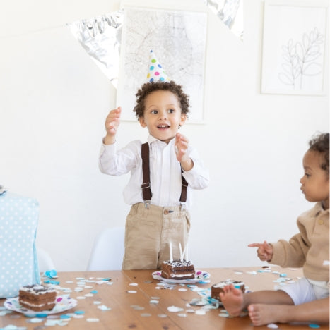  little boy celebrating his birthday with cake and candles around a confetti filled table, wearing an outfit similar to what you can find at Asdelia Mae Children's Clothing Boutique